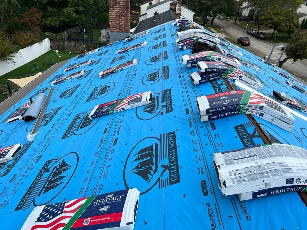 Heritage shingle bundles on blue synthetic underlayment during roof replacement