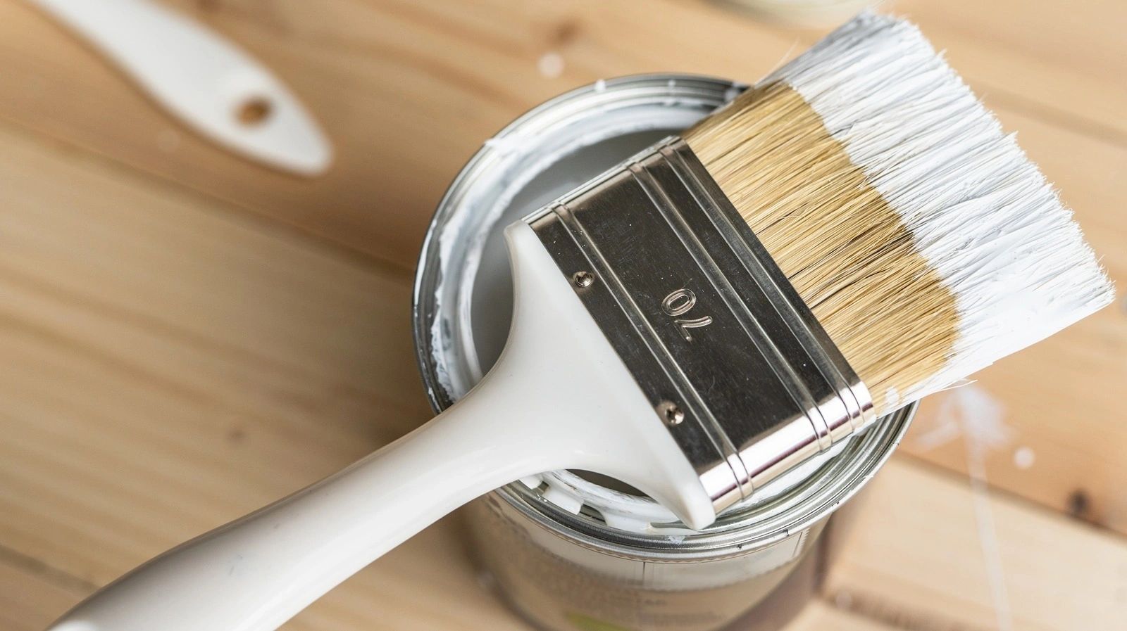 White paint brush resting on open paint can ready for interior painting
