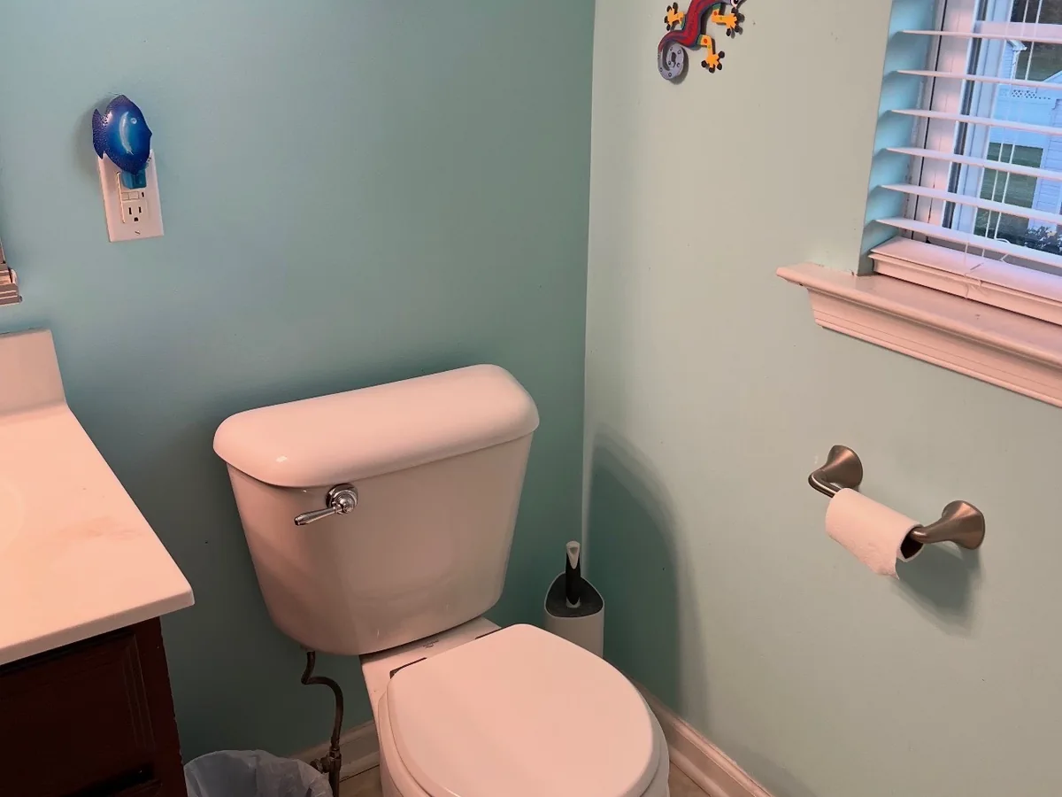 Bathroom before renovation showing worn vinyl tile flooring and dated fixtures in Bucks County PA