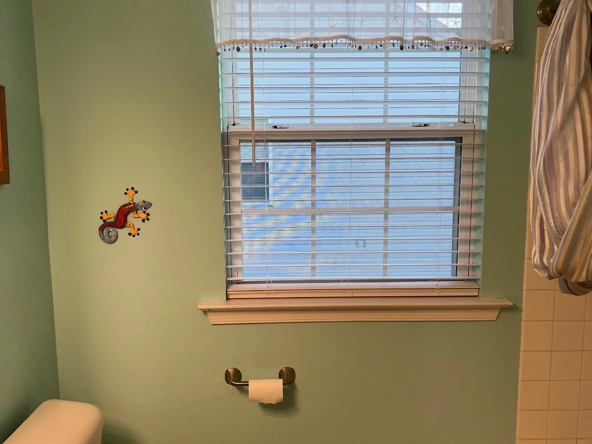Bathroom tub and window wall before renovation with dated tile and vinyl flooring in Bucks County PA