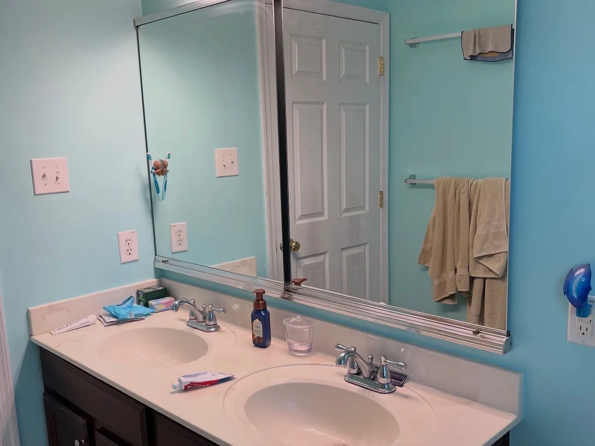 Bathroom vanity wall before renovation with dark cabinets and cultured marble top in Bucks County PA