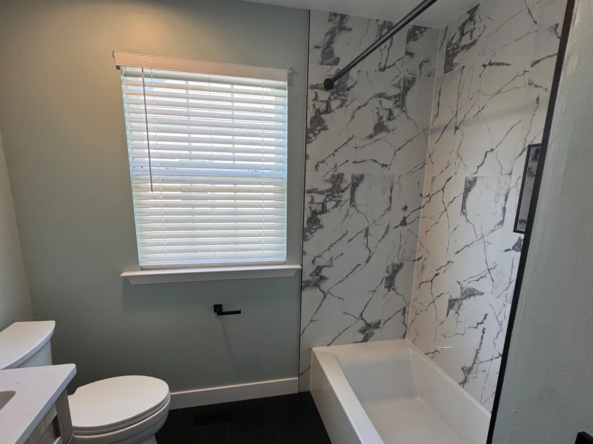 Soaking tub with full-height marble-look porcelain tile surround and slate tile floor by Altieri and Sons in Bucks County PA