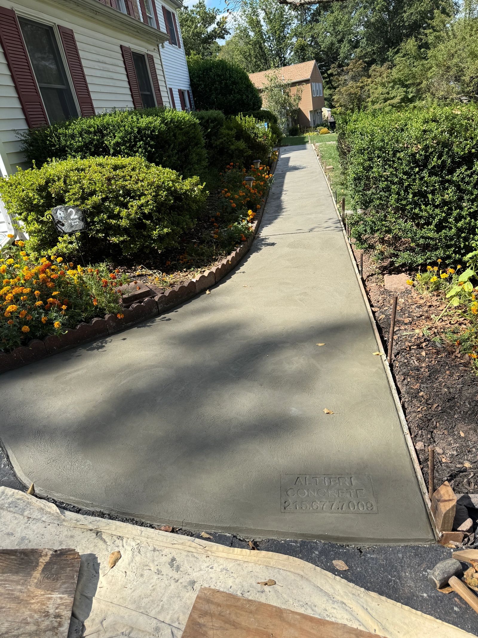Freshly poured concrete walkway stamped with Altieri and Sons logo