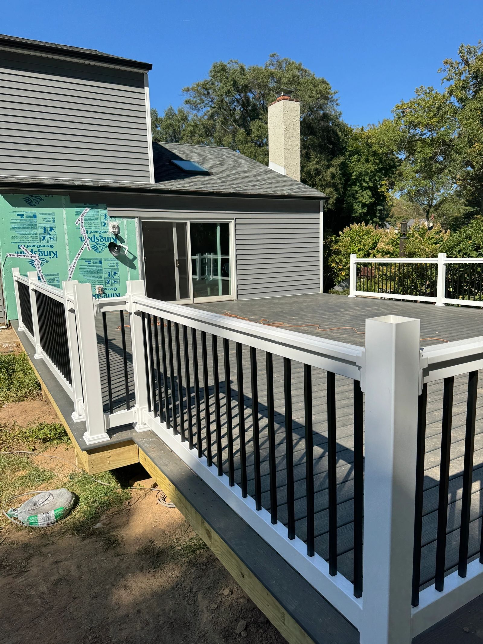 Completed composite deck with white vinyl posts and black aluminum balusters