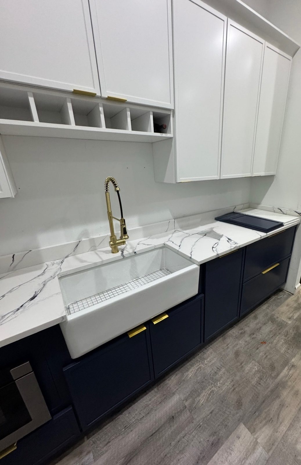 Navy blue cabinets with marble countertops, farmhouse sink, and brass fixtures