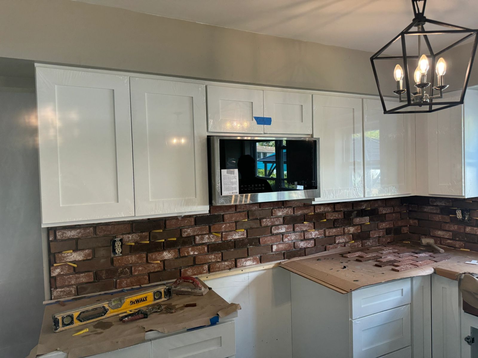 Kitchen renovation with exposed brick backsplash and white shaker cabinets