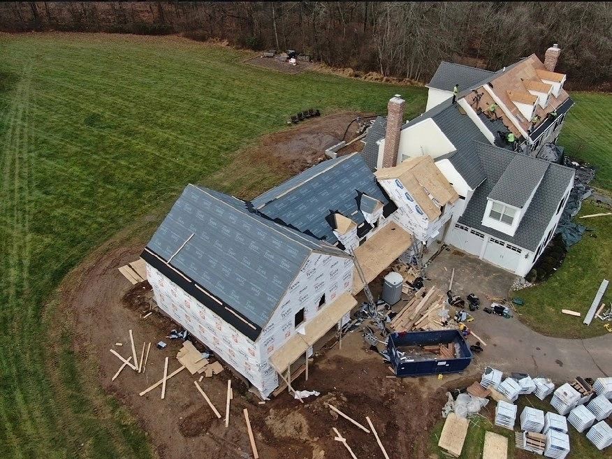 Aerial view of large home during roof and siding renovation with house wrap visible