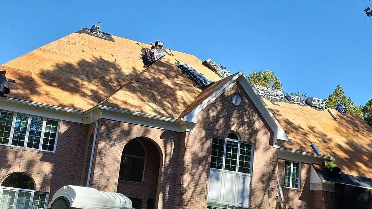Roof replacement in progress on large brick home by Altieri and Sons