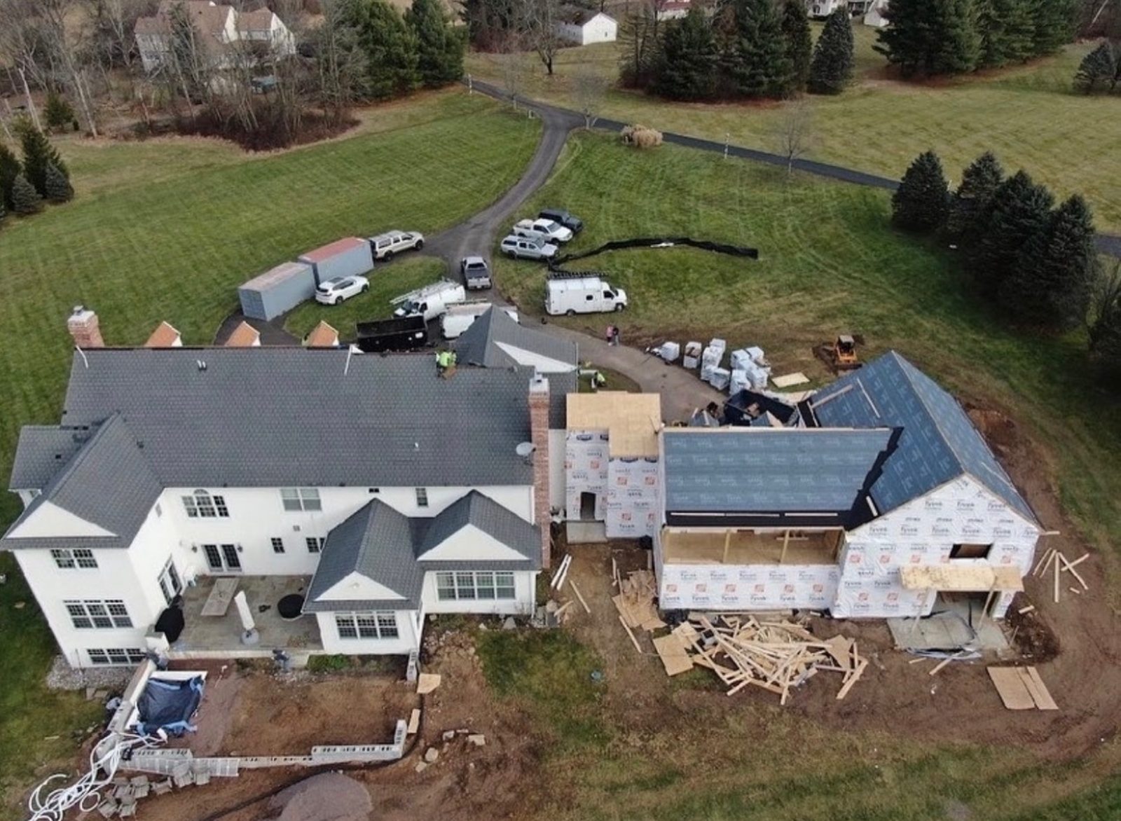 Aerial drone view of large residential roof and addition project with new shingle installation in progress
