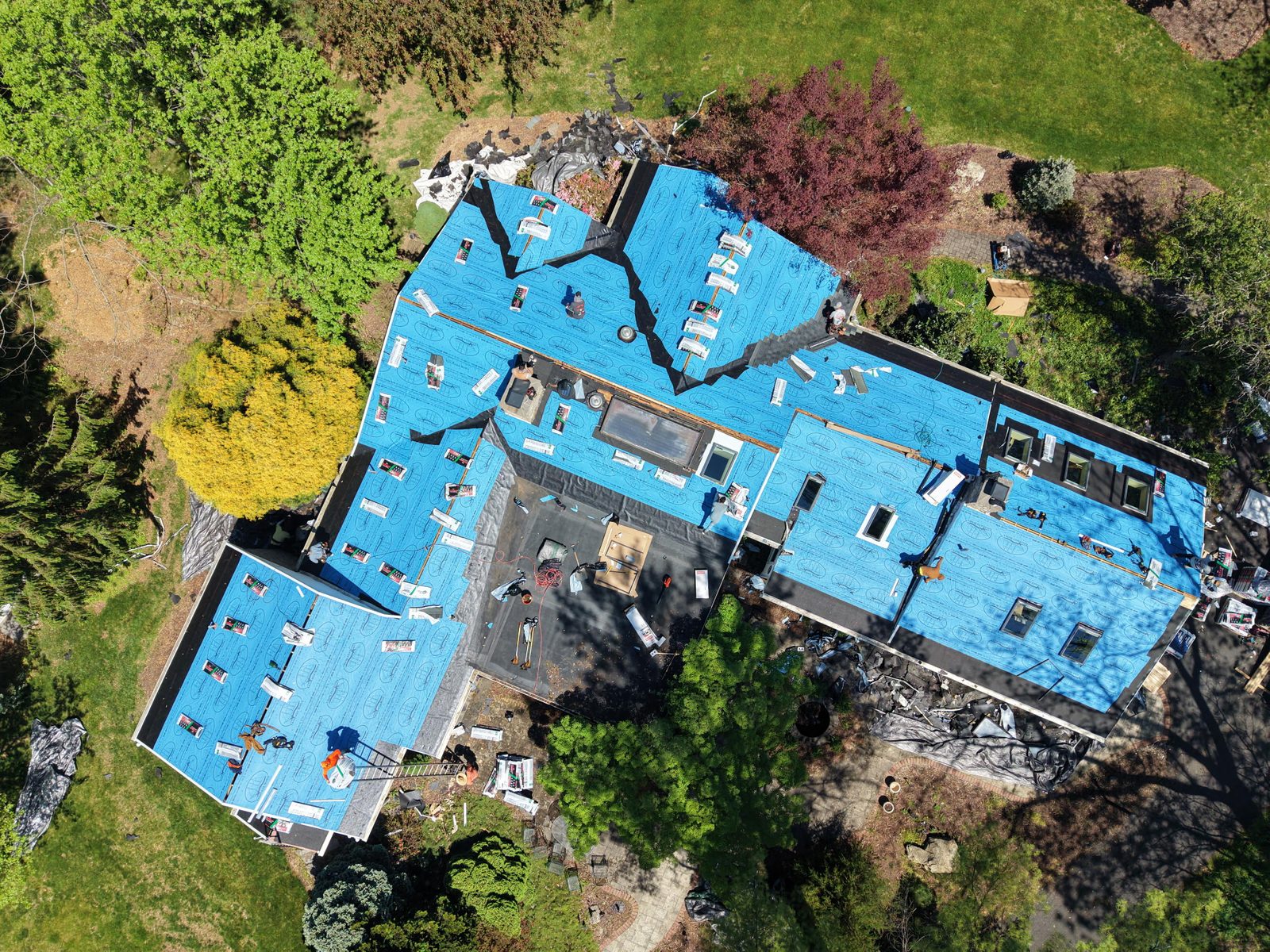 Aerial view of a large home mid roof replacement with blue synthetic underlayment installed by Altieri and Sons