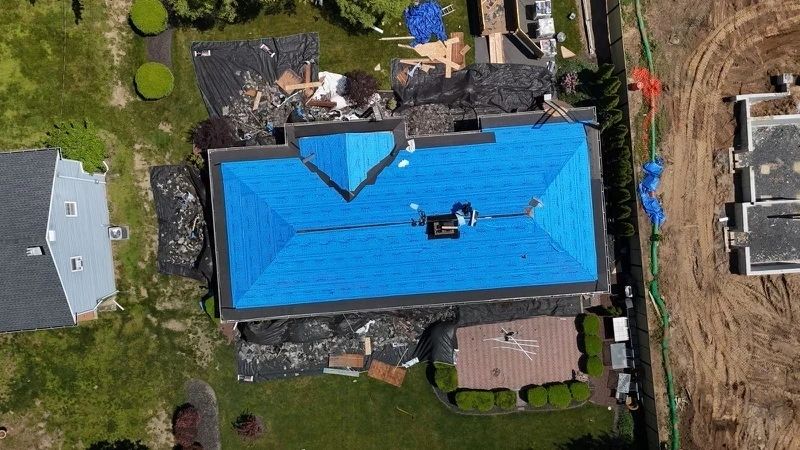 Aerial view of blue synthetic underlayment during roof replacement with old shingles removed