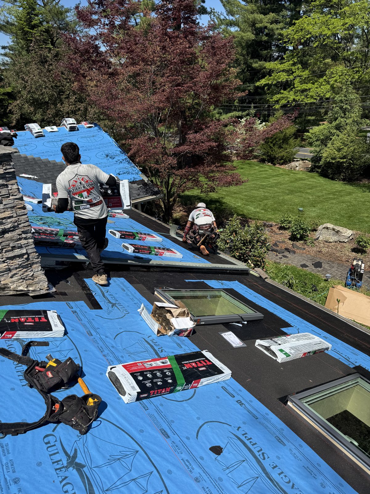 Altieri and Sons crew working near dormer window during roof replacement with blue synthetic wrap visible