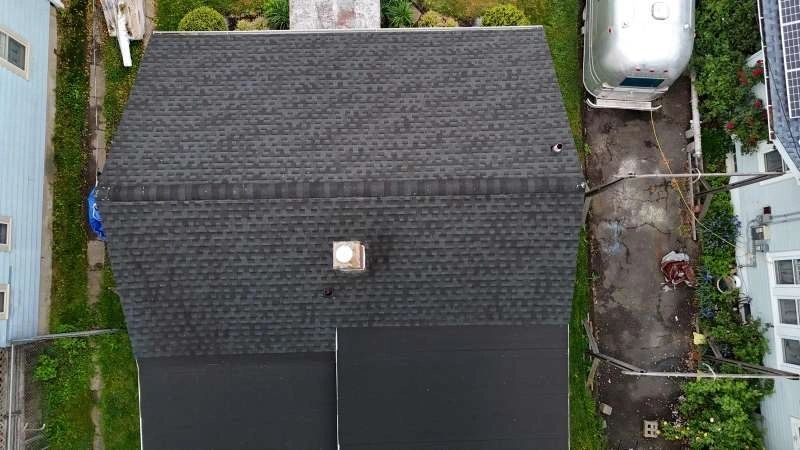 Aerial view of completed dark architectural shingle roof with skylight