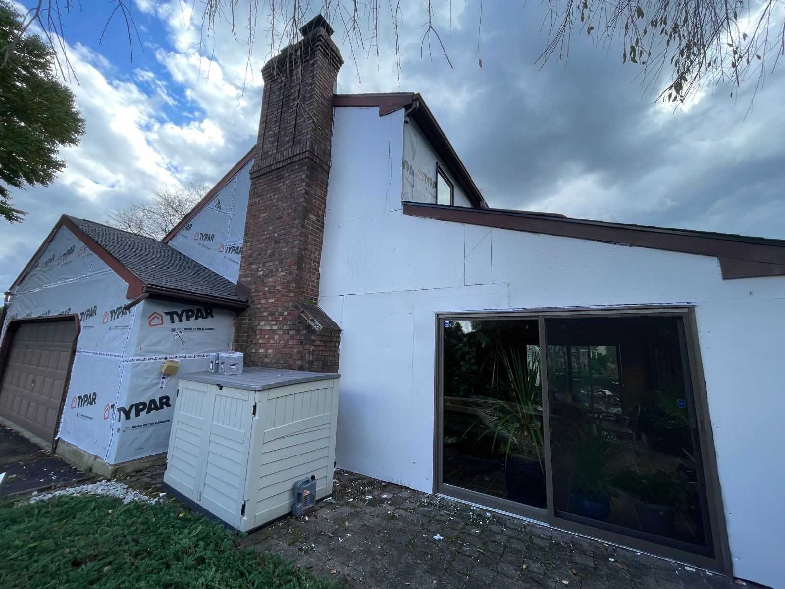Home with TYPAR house wrap and foam insulation during siding replacement with brick chimney